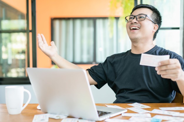 Man checking results of lottery on laptop and winning